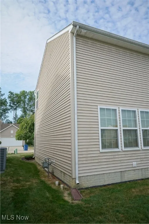 View of side of property with a lawn and crawl space