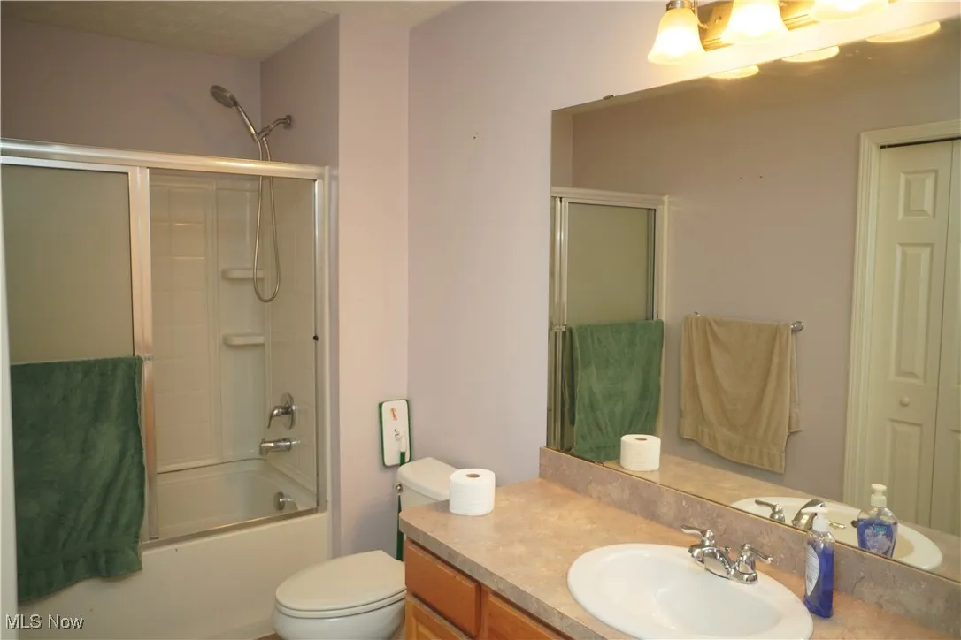 Bathroom with combined bath / shower with glass door and vanity