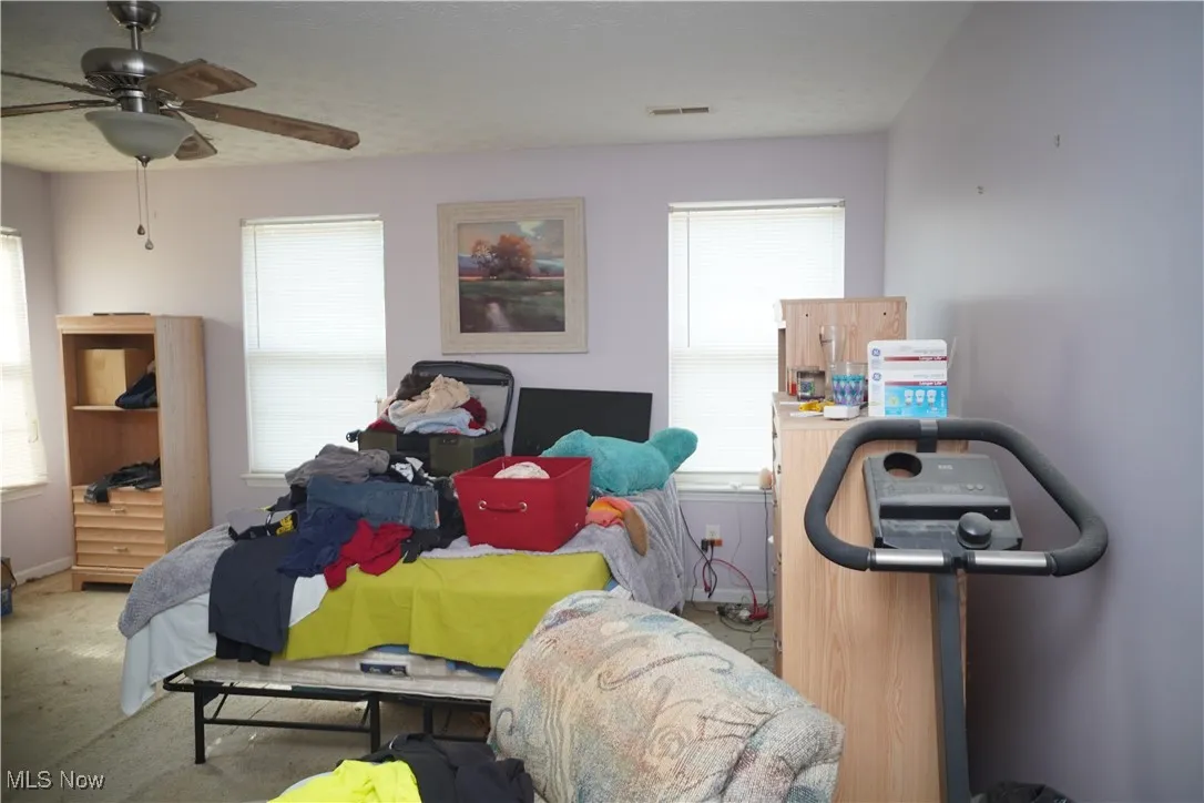 Bedroom with carpet flooring, a ceiling fan, and a textured ceiling