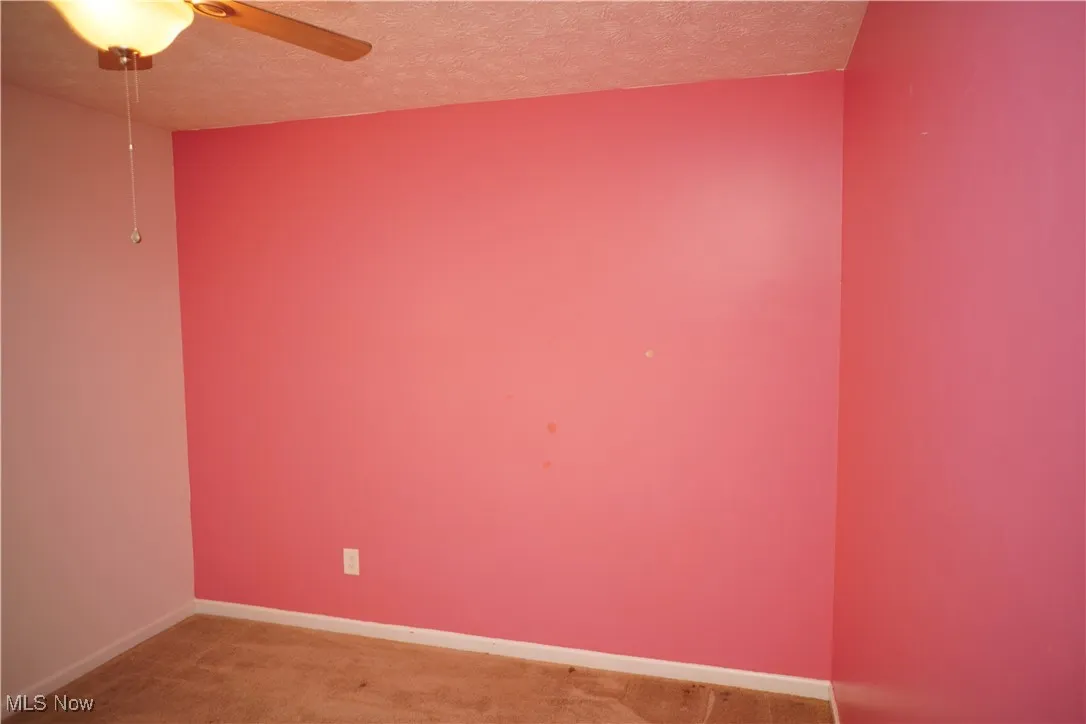 Carpeted spare room featuring a textured ceiling and ceiling fan