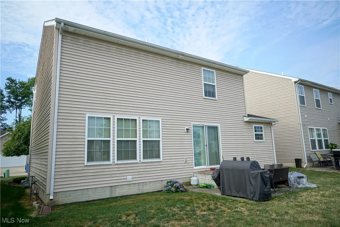 Back of house with a yard and a patio