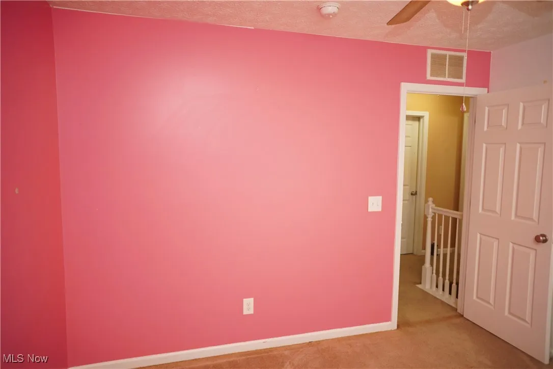 Carpeted spare room with ceiling fan and a textured ceiling