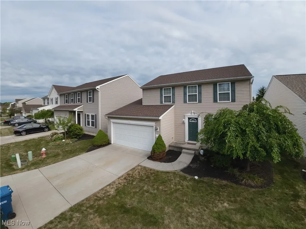 Colonial inspired home with driveway, a garage, and a front lawn