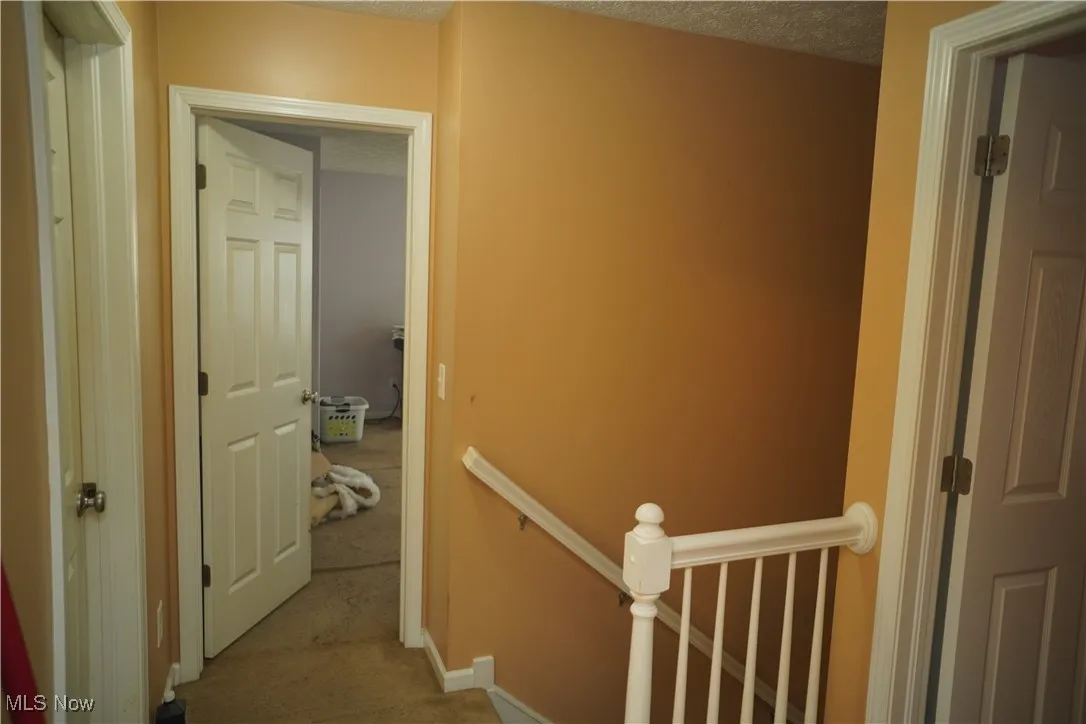Hall with an upstairs landing, a textured ceiling, and carpet