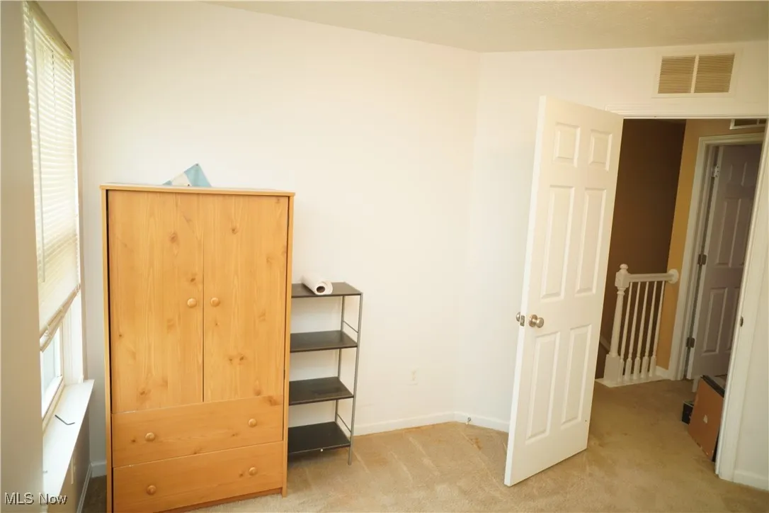Unfurnished bedroom featuring light carpet and baseboards