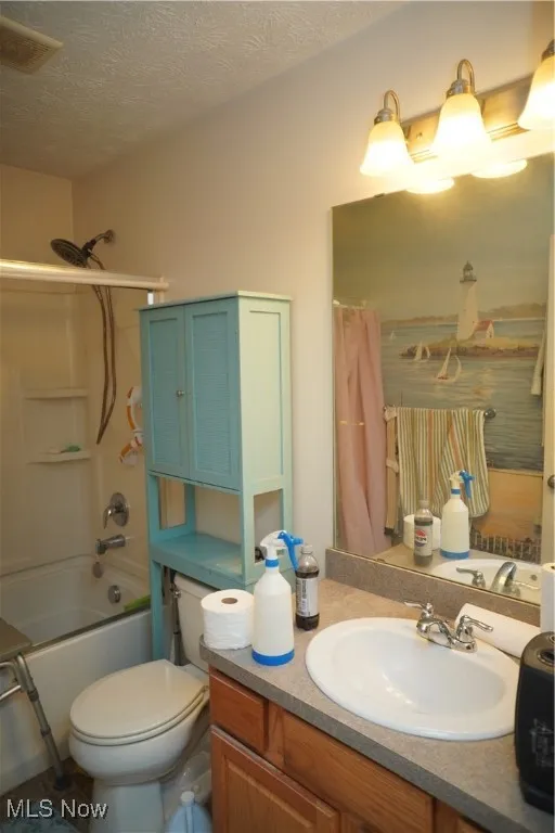 Bathroom with shower / bathtub combination with curtain, vanity, and a textured ceiling