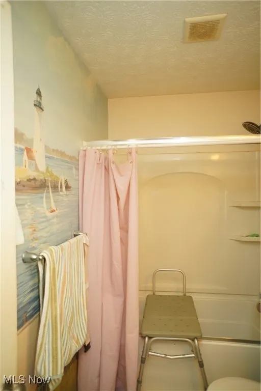 Bathroom featuring a textured ceiling and shower / tub combo