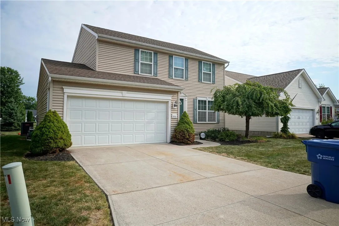 View of front of house with a shingled roof, concrete driveway, a garage, and a front lawn