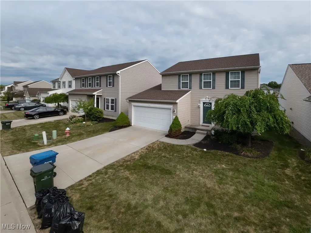 View of front facade with driveway, a front yard, and roof with shingles