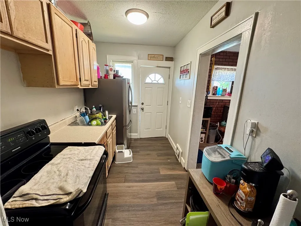Kitchen with black electric range, a textured ceiling, dark wood-style flooring, light countertops, and healthy amount of natural light
