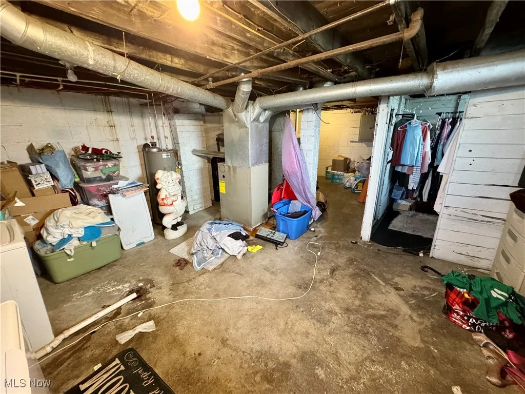 Unfinished basement featuring water heater, heating unit, and electric panel
