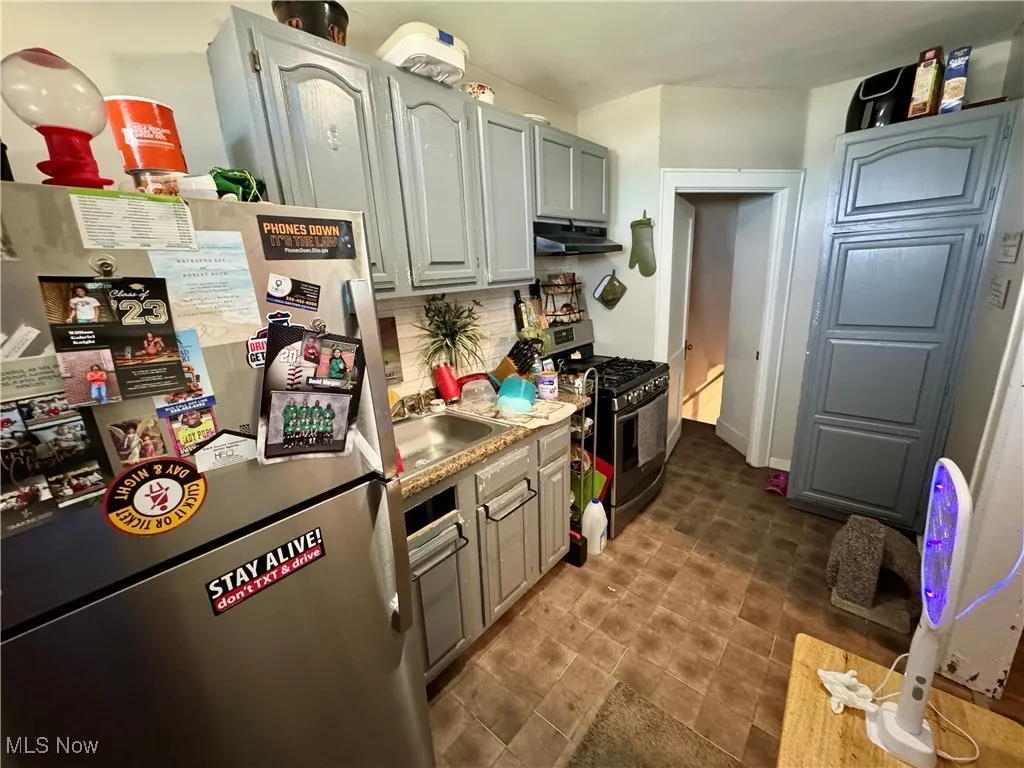 Kitchen with stainless steel appliances, backsplash, and under cabinet range hood