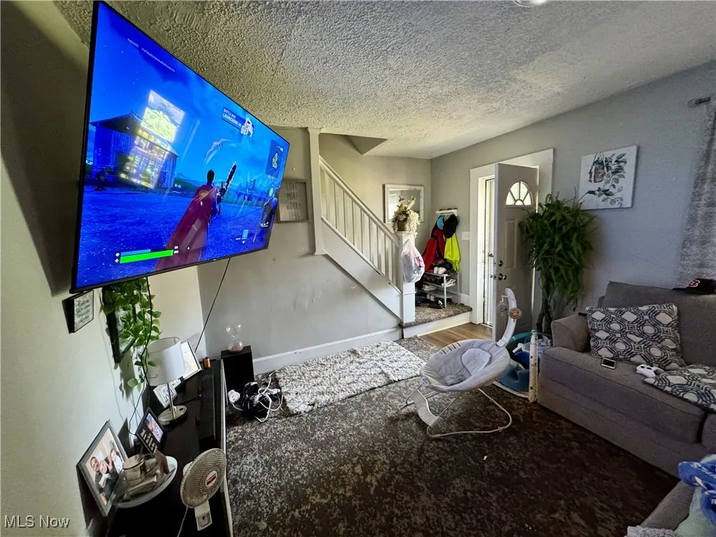 Living room featuring stairway and a textured ceiling