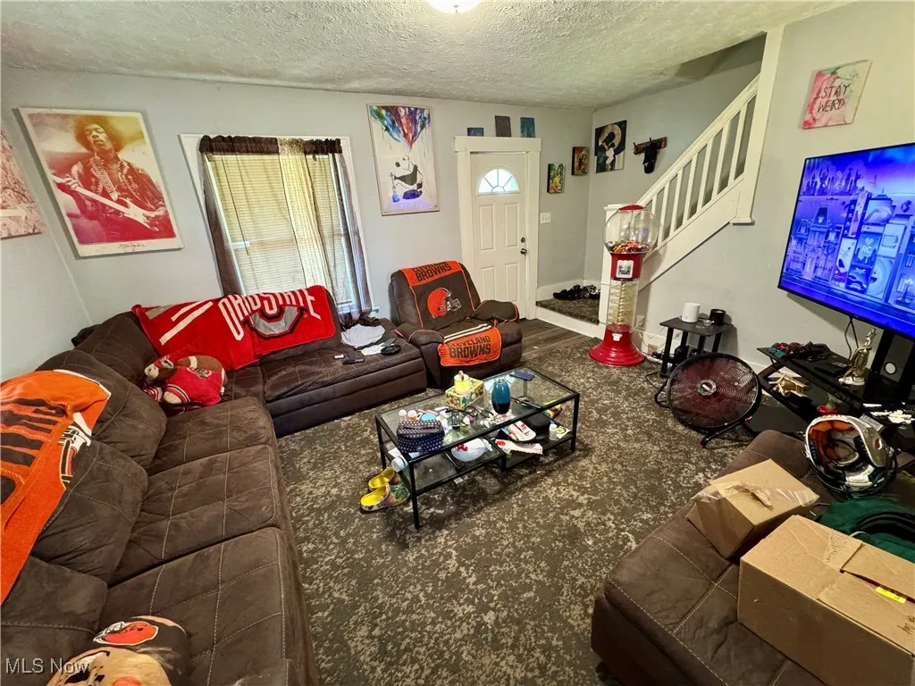Living room featuring a textured ceiling and stairway
