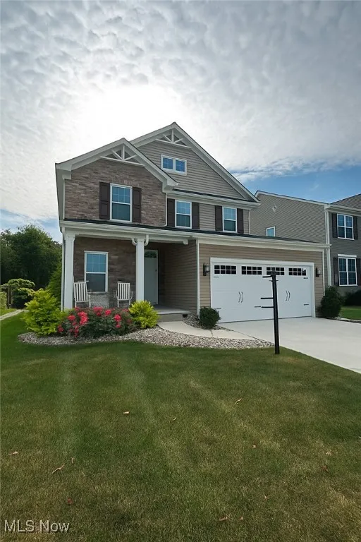 View of front of house featuring covered porch, a front yard, concrete driveway, and a garage