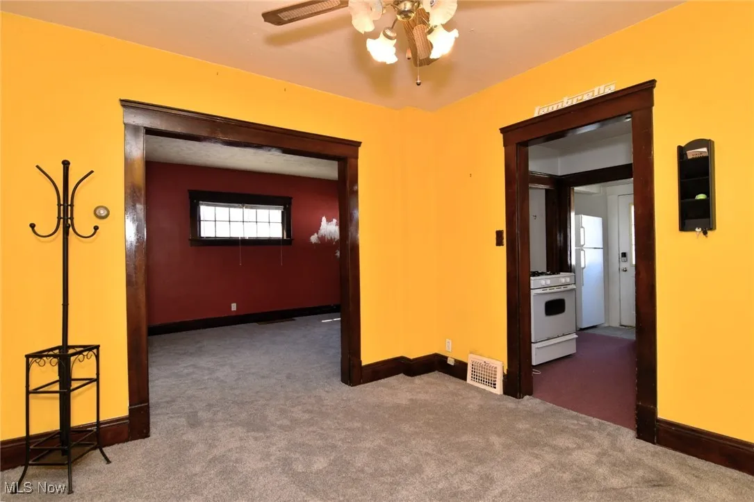 Carpeted spare room featuring baseboards and ceiling fan