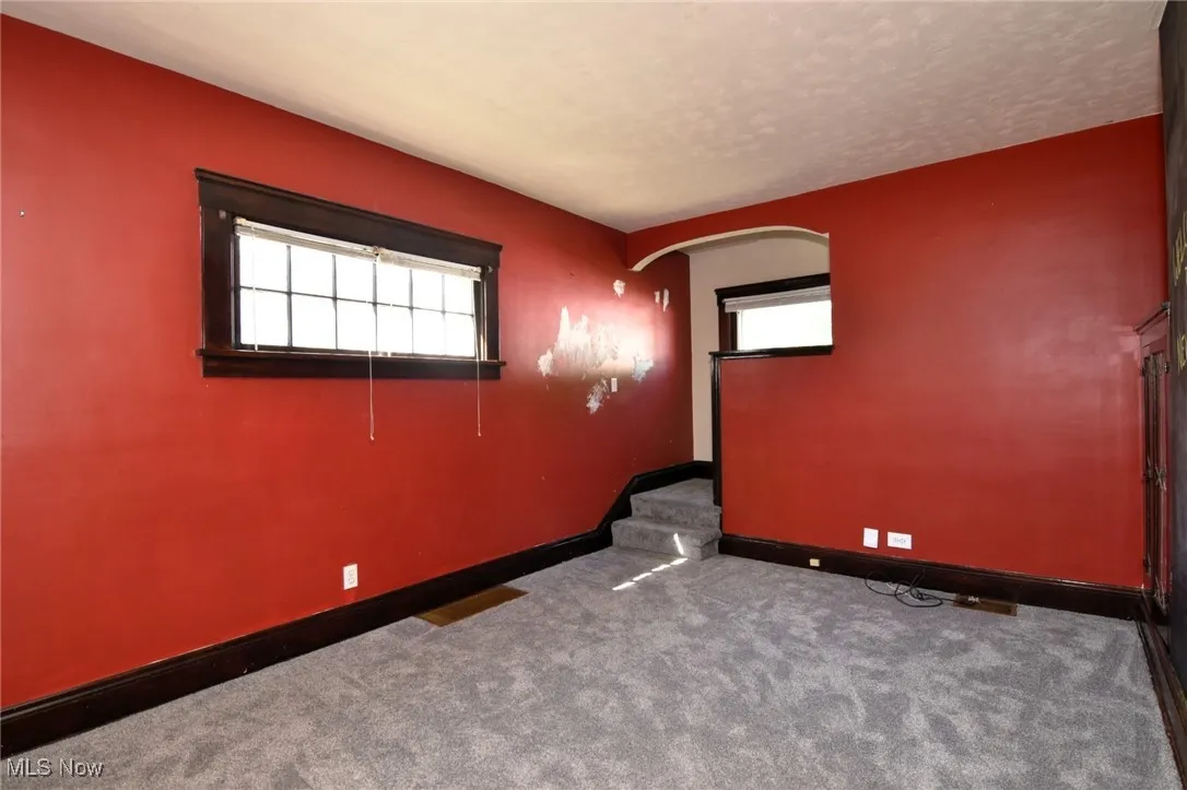 Unfurnished room featuring arched walkways, carpet floors, and a textured ceiling