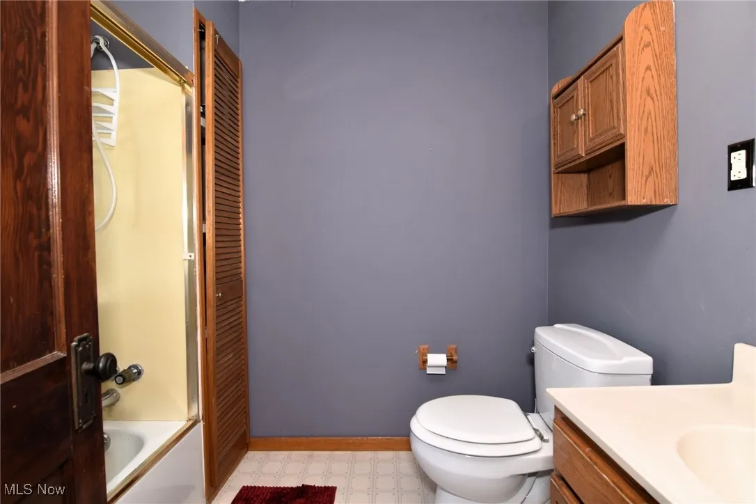 Full bath featuring vanity, bathtub / shower combination, light floors, and a closet