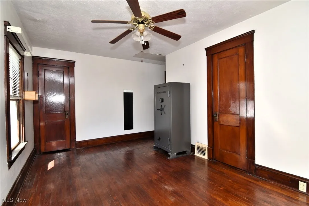 Unfurnished room with dark wood-style flooring, a textured ceiling, and ceiling fan