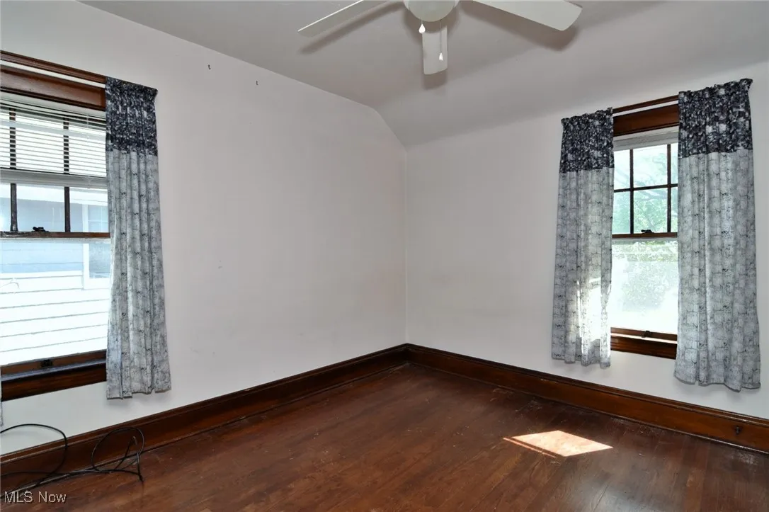 Empty room with wood-type flooring, vaulted ceiling, and a ceiling fan