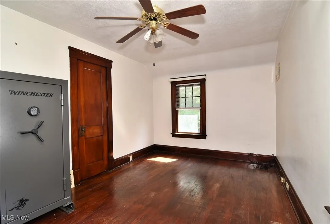 Spare room featuring dark wood-type flooring, a textured ceiling, lofted ceiling, and a ceiling fan