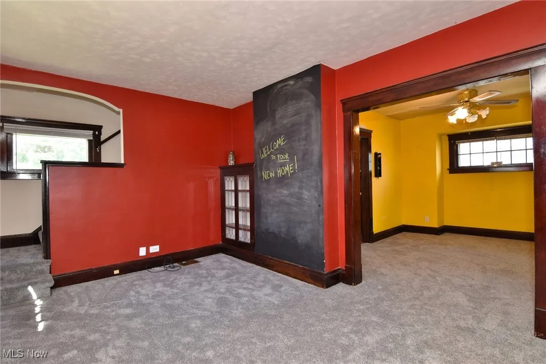 Empty room featuring healthy amount of natural light, carpet, a textured ceiling, and a ceiling fan