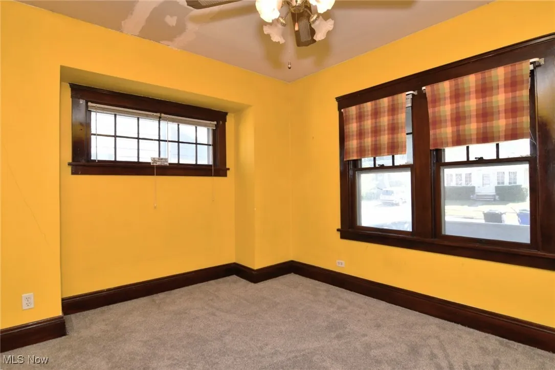 Carpeted empty room with baseboards and a ceiling fan