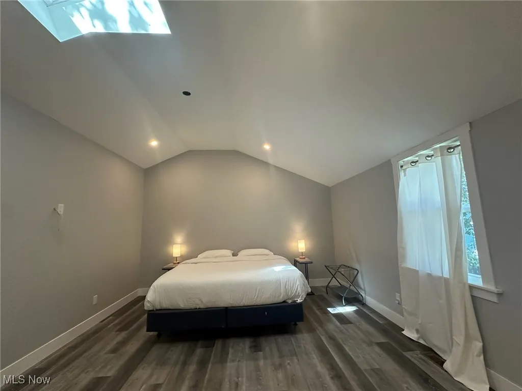 Bedroom featuring multiple windows, lofted ceiling, dark wood-type flooring, and a skylight