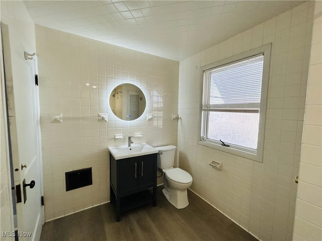 Bathroom with tile walls, dark wood finished floors, and vanity