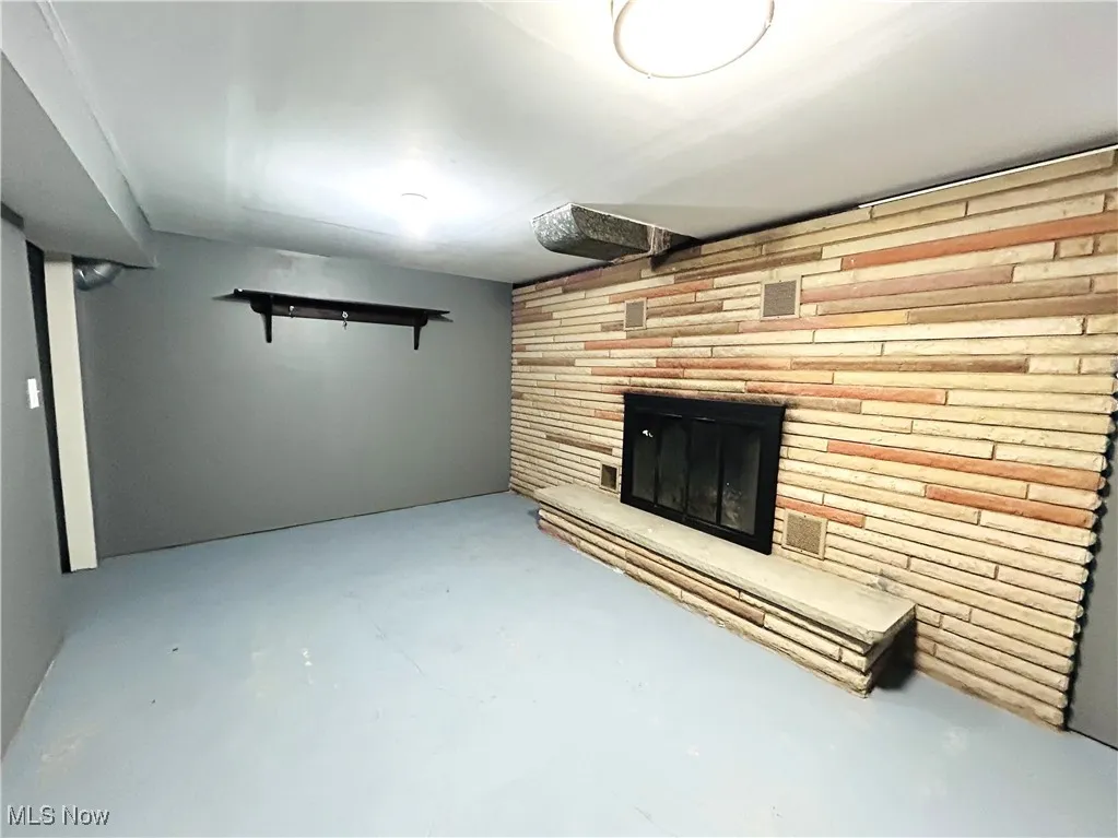 Bonus room with a brick fireplace and concrete flooring