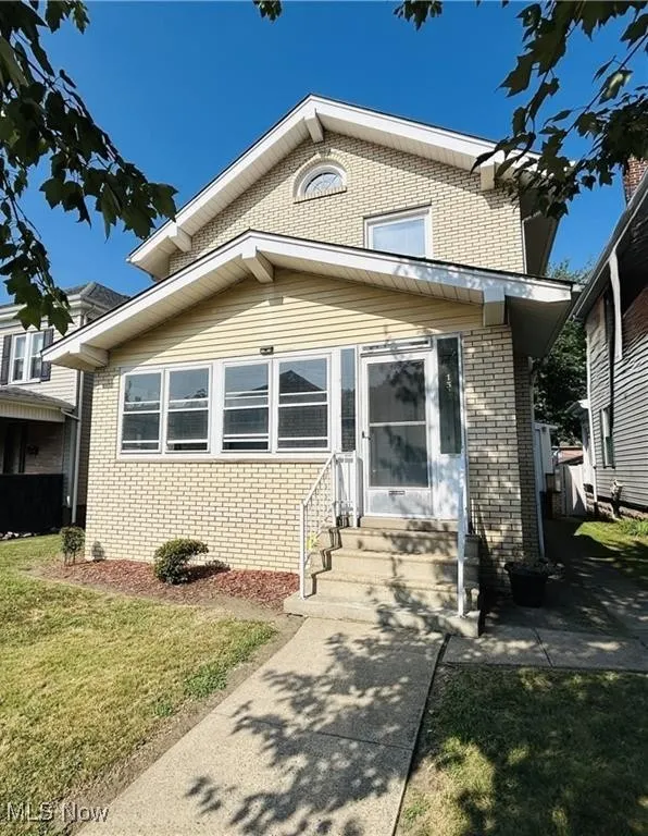View of front of home featuring a front yard, entry steps, and brick siding