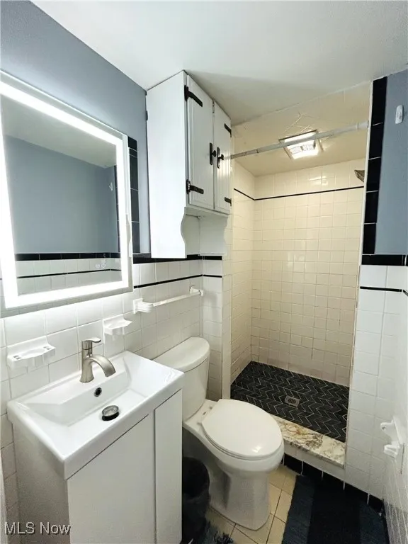 Bathroom featuring vanity, toilet, and a stall shower