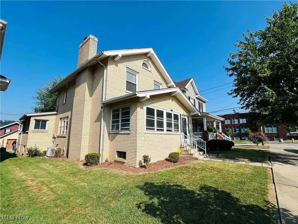 View of side of home featuring brick siding, and a yard
