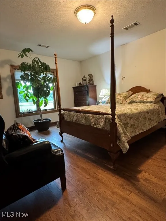 Bedroom with wood finished floors and a textured ceiling