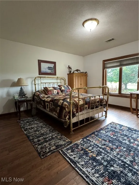 Bedroom with wood finished floors and a textured ceiling