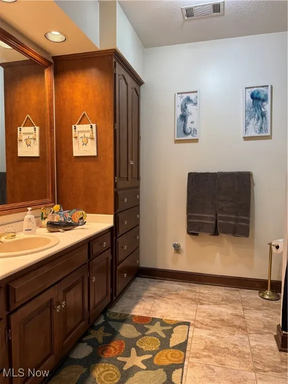 Bathroom with vanity, light tile patterned floors, and a textured ceiling