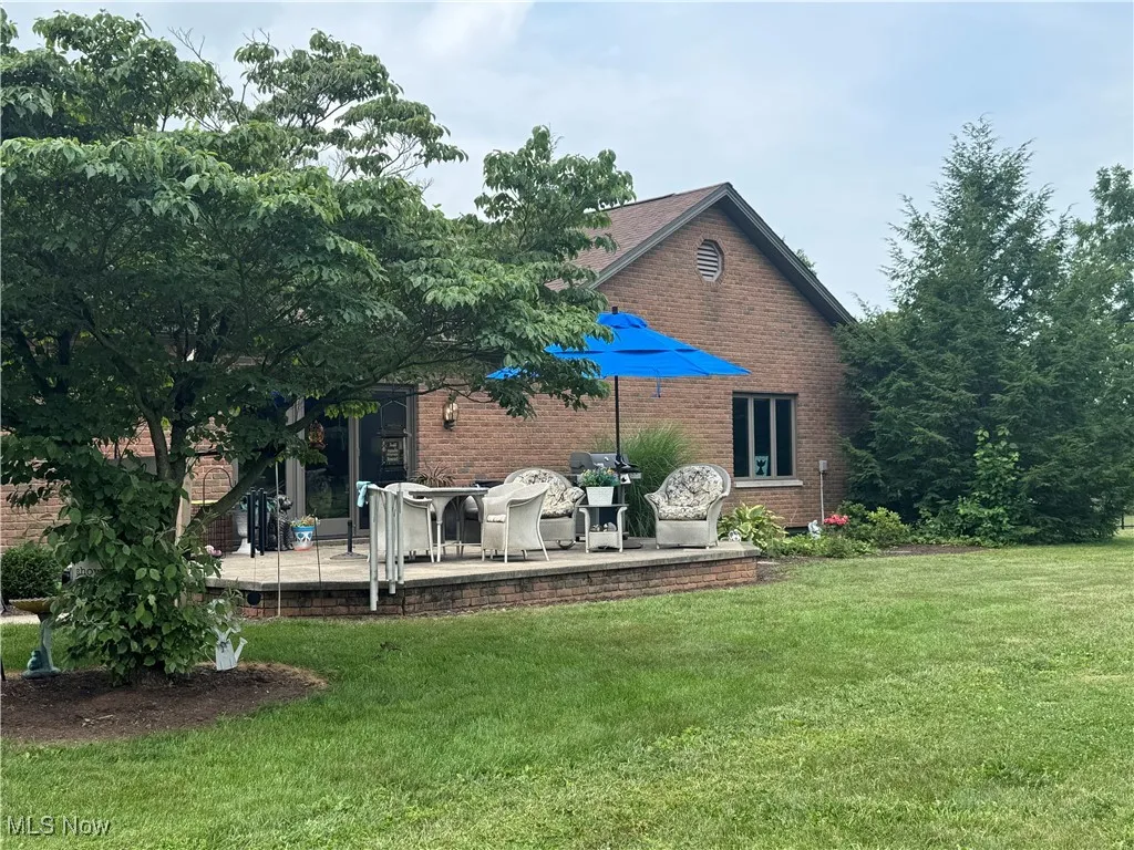 Back of property with a deck, a yard, and brick siding