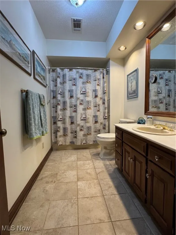 Bathroom featuring vanity, a textured ceiling, light tile patterned floors, and a shower with curtain