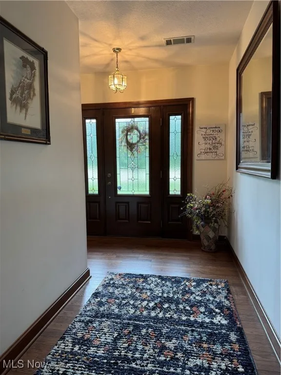 Foyer entrance featuring plenty of natural light, a textured ceiling, wood finished floors, and a chandelier