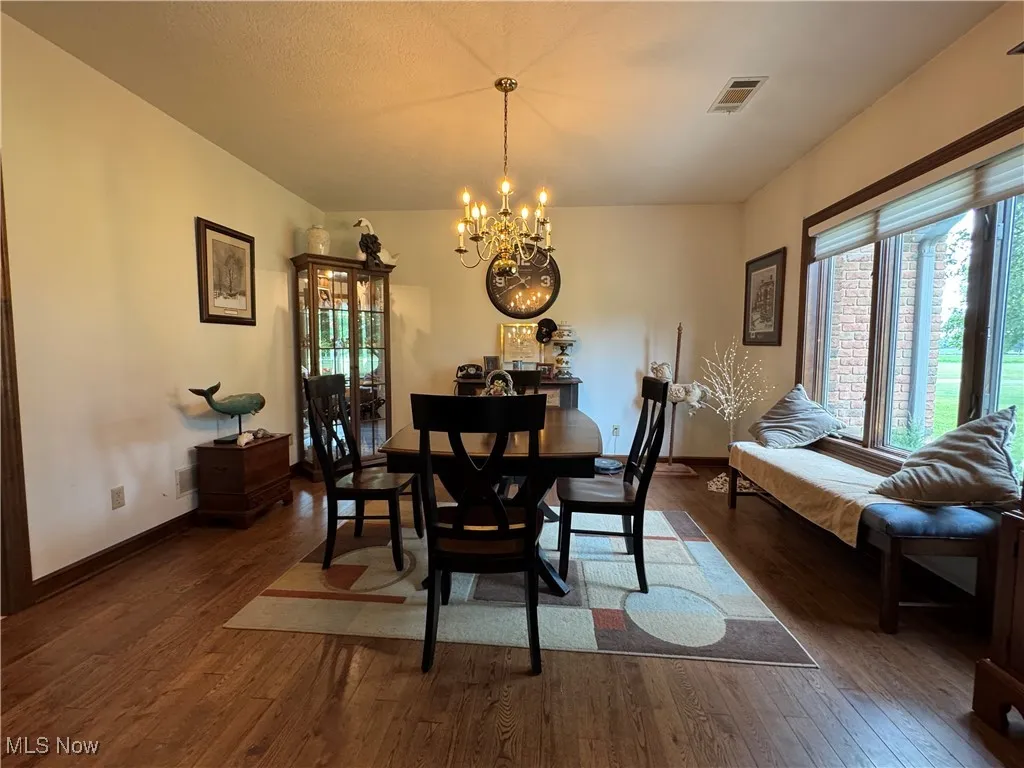 Dining room featuring dark wood finished floors, a chandelier, and plenty of natural light