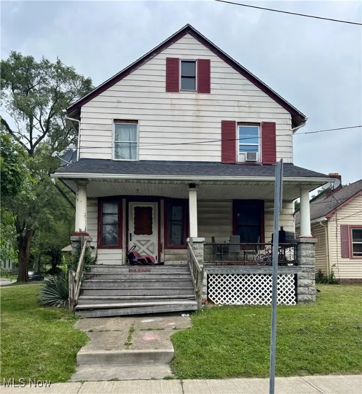 American foursquare style home featuring a front lawn and covered porch