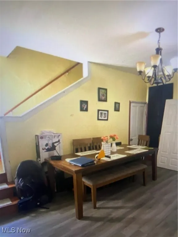 Dining space with dark wood-type flooring and a chandelier