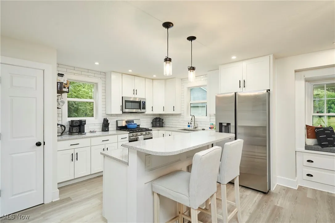 Kitchen with appliances with stainless steel finishes, healthy amount of natural light, tasteful backsplash, white cabinets, and recessed lighting