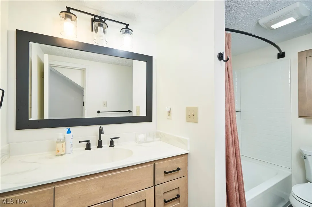 Full bathroom with shower / bath combination with curtain, vanity, and a textured ceiling