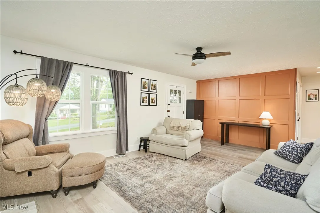Living room with light wood finished floors, ceiling fan, and a textured ceiling