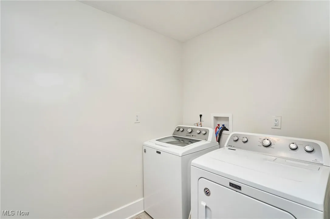 Washroom featuring independent washer and dryer and baseboards