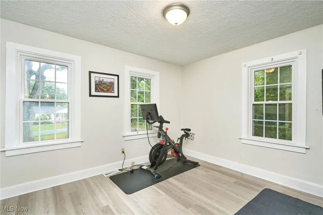 Workout area featuring a textured ceiling and light wood finished floors