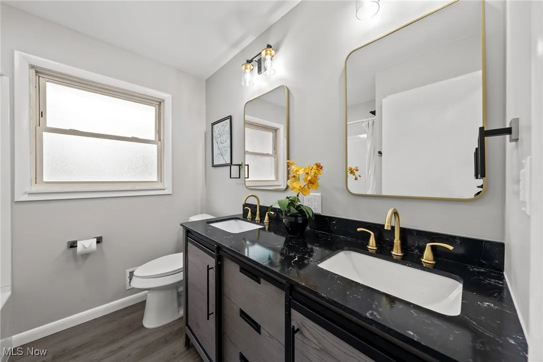 Bathroom featuring dark wood finished floors, double vanity, and curtained shower