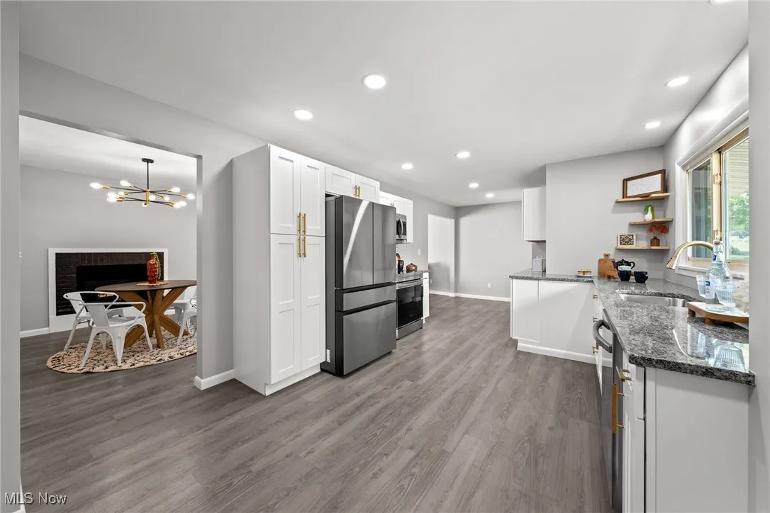 Kitchen with dark stone countertops, open shelves, stainless steel appliances, white cabinets, and recessed lighting