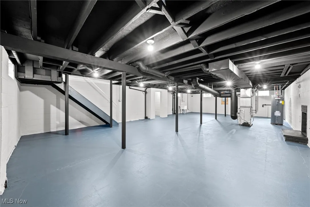 Below grade area featuring electric water heater, heating unit, and stairway